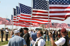 A group gathers holding the American flag in support of Veteran's Day.